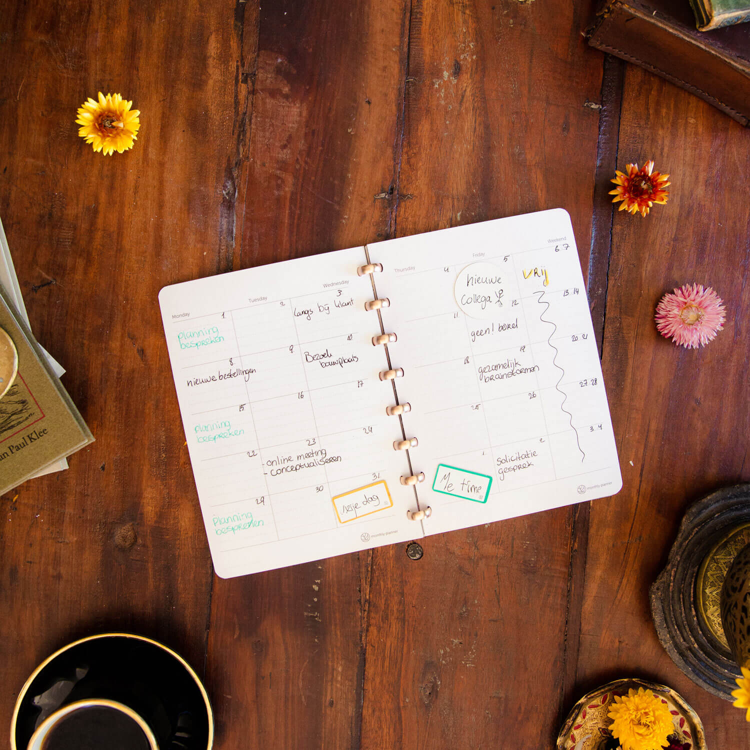 een whiteboard schrift opgengeslagen op een houten tafel met uitwisbare maandplanner vellen